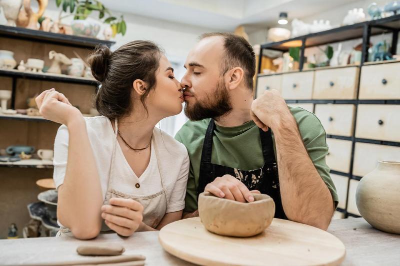 Couple enjoying a pottery class together in Auckland, shaping clay on a wheel in a creative workshop setting